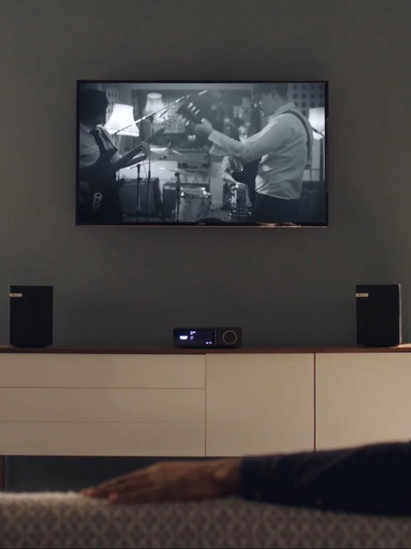 A man engrossed in a movie on a TV in his living room.